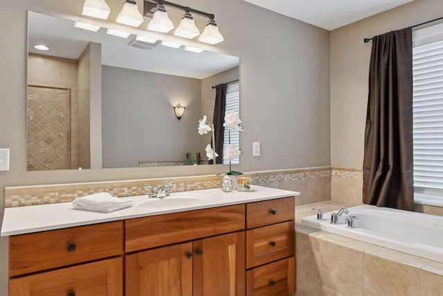 bathroom featuring vanity and a relaxing tiled tub