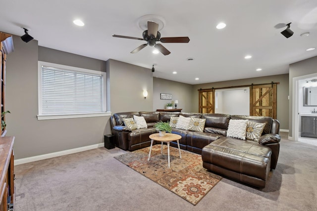 carpeted living room featuring ceiling fan and a barn door