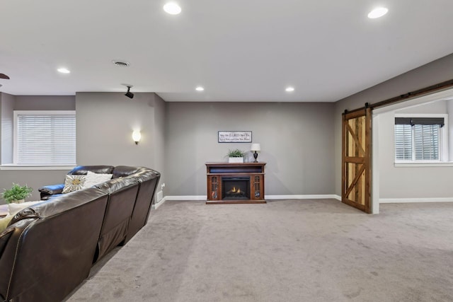 living room with a barn door and carpet flooring