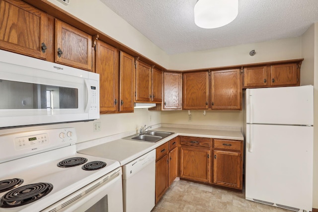 kitchen featuring light countertops, white appliances, a sink, and brown cabinets