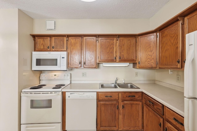 kitchen with a textured ceiling, white appliances, a sink, light countertops, and brown cabinets