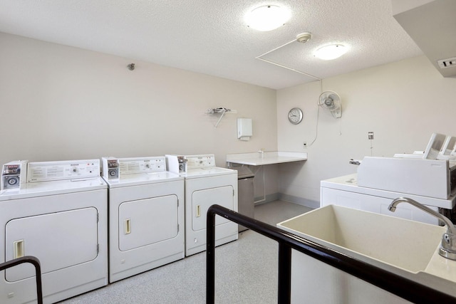 shared laundry area featuring a textured ceiling, separate washer and dryer, a sink, and visible vents