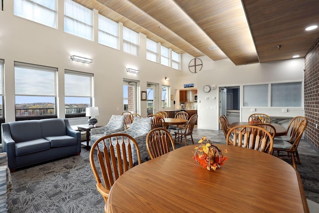 dining room featuring wood ceiling and a towering ceiling