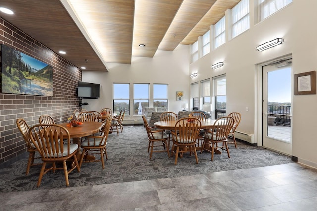 dining room with wood ceiling, a high ceiling, and a wealth of natural light