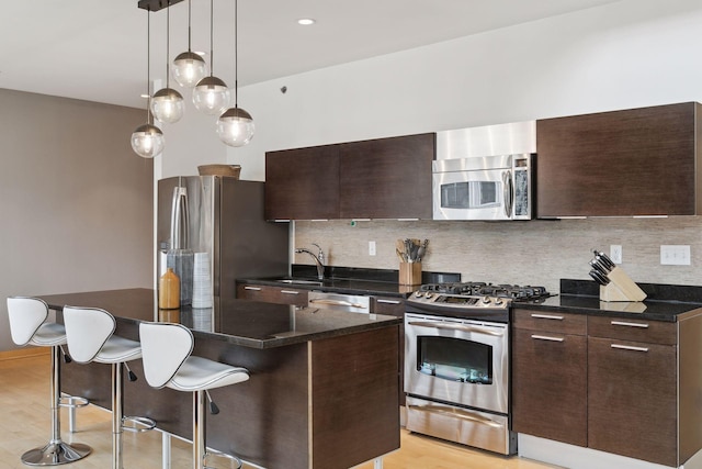 kitchen with light hardwood / wood-style floors, stainless steel appliances, dark brown cabinetry, and a center island