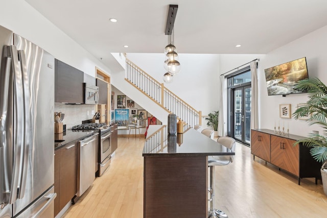 kitchen with hanging light fixtures, a breakfast bar, light hardwood / wood-style flooring, a kitchen island, and appliances with stainless steel finishes