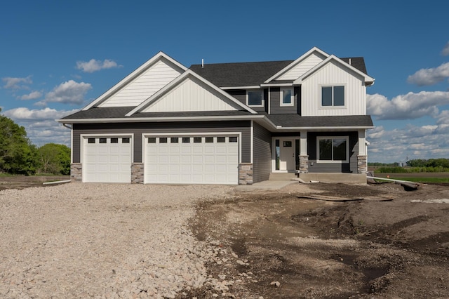 25341 Delmar Ave, New Prague, MN 56071 - view of front of house featuring stone siding, covered porch, driveway, an attached garage, and roof with shingles