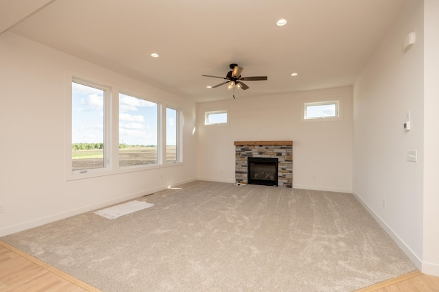 25341 Delmar Ave, New Prague, MN 56071 - unfurnished living room featuring a ceiling fan, a stone fireplace, light carpet, baseboards, and recessed lighting
