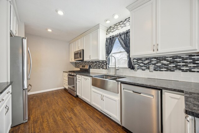 kitchen featuring sink, dark hardwood / wood-style floors, dark stone countertops, white cabinets, and appliances with stainless steel finishes