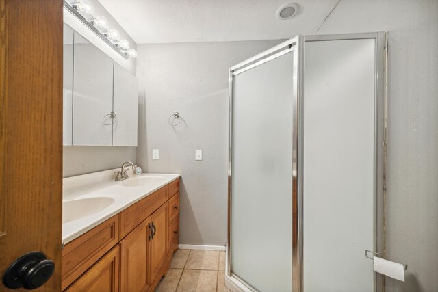 bathroom featuring tile patterned flooring, vanity, a shower with shower door, and a textured ceiling