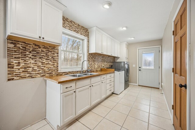 kitchen featuring butcher block countertops, decorative backsplash, white cabinetry, and sink