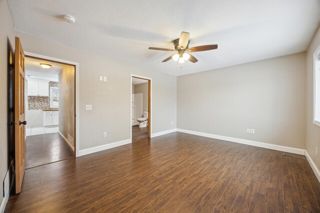 unfurnished room featuring a wealth of natural light, a textured ceiling, dark hardwood / wood-style floors, and ceiling fan