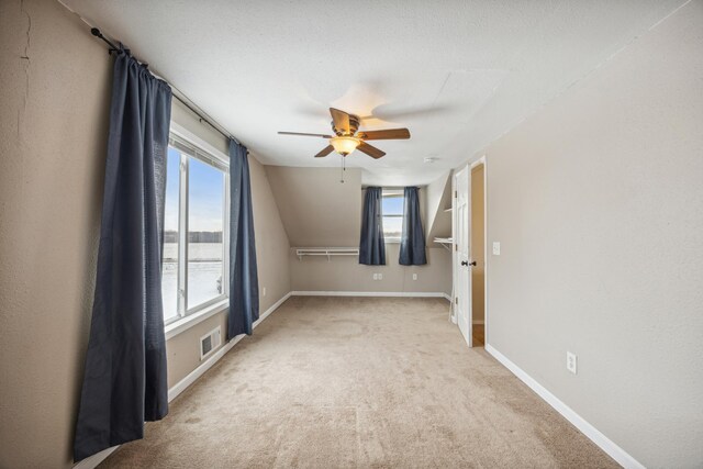 carpeted empty room with ceiling fan and a water view