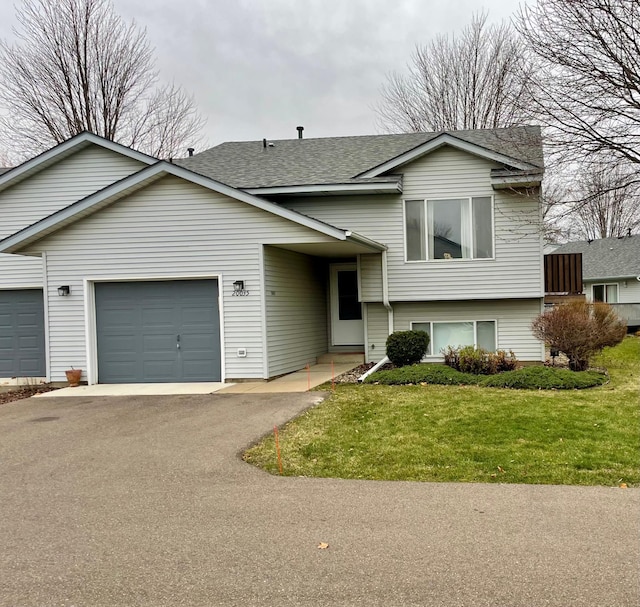 tri-level home featuring a garage and a front lawn