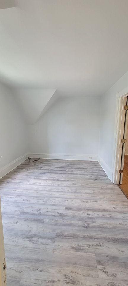 bonus room featuring light wood-type flooring and vaulted ceiling