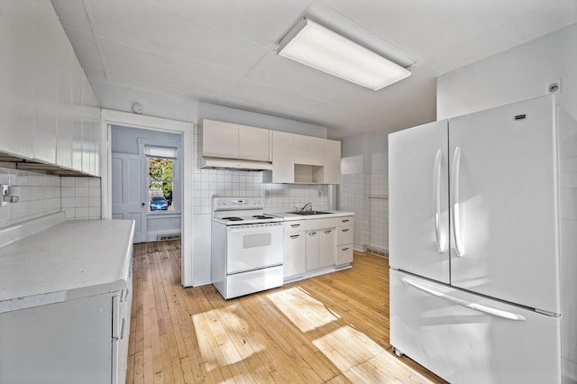 kitchen with white appliances, white cabinets, sink, light hardwood / wood-style flooring, and tasteful backsplash