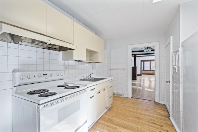 kitchen with sink, light wood-type flooring, extractor fan, and white electric stove