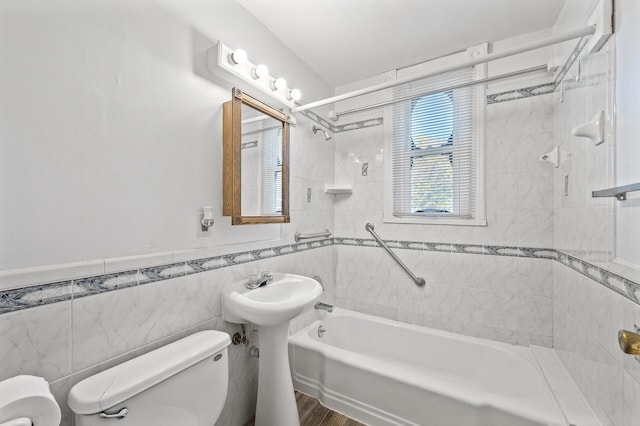 bathroom with tiled shower / bath, hardwood / wood-style flooring, toilet, and tile walls