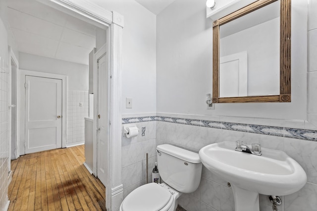 bathroom featuring hardwood / wood-style flooring, toilet, tile walls, and sink