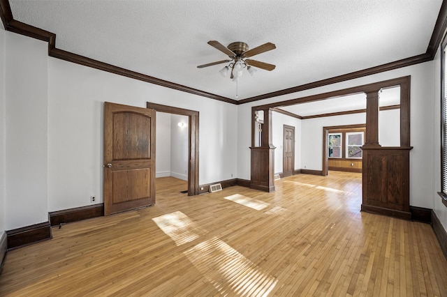 spare room featuring ornate columns, a textured ceiling, and light hardwood / wood-style flooring