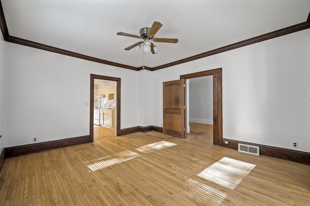 empty room featuring ceiling fan, ornamental molding, a textured ceiling, and light wood-type flooring