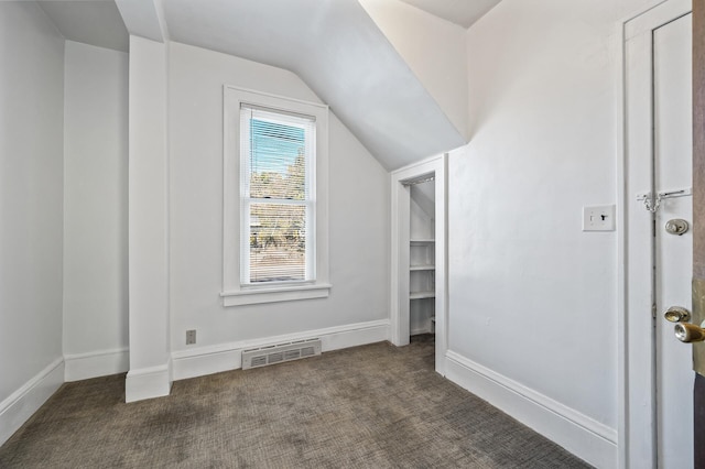 additional living space with dark colored carpet and vaulted ceiling