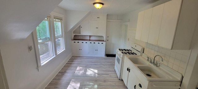 kitchen with decorative backsplash, white cabinetry, white gas stove, and light wood-type flooring