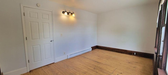 empty room featuring wood-type flooring and a baseboard heating unit