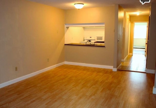 unfurnished room featuring hardwood / wood-style flooring and a baseboard radiator