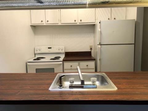 kitchen with butcher block counters, white cabinetry, sink, and white appliances