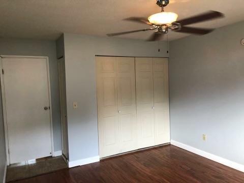 unfurnished bedroom featuring a closet, ceiling fan, and dark wood-type flooring