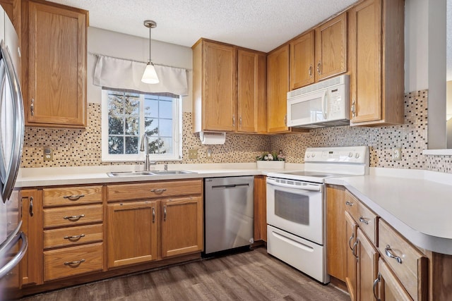 kitchen with dark wood-type flooring, sink, a textured ceiling, decorative light fixtures, and stainless steel appliances