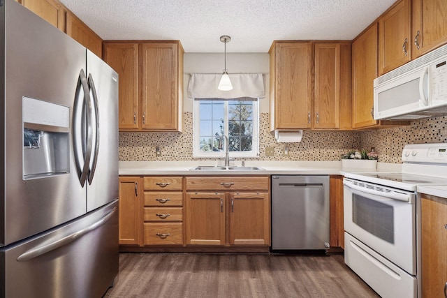 kitchen with sink, dark wood-type flooring, hanging light fixtures, a textured ceiling, and appliances with stainless steel finishes