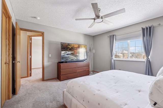 bedroom featuring a textured ceiling, light colored carpet, and ceiling fan