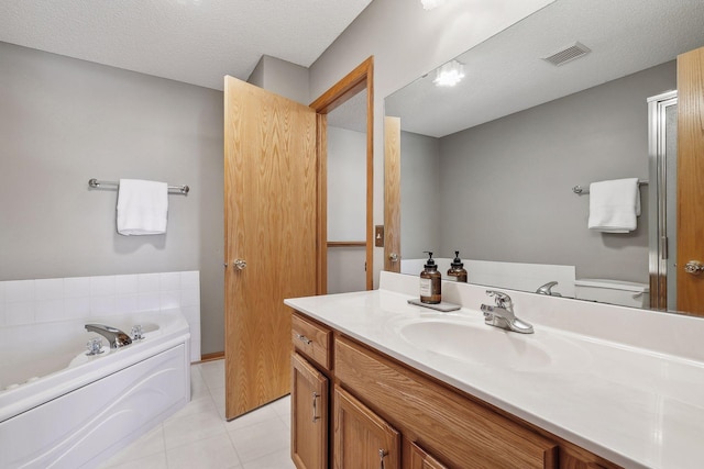 bathroom with tile patterned floors, a bathing tub, vanity, and a textured ceiling