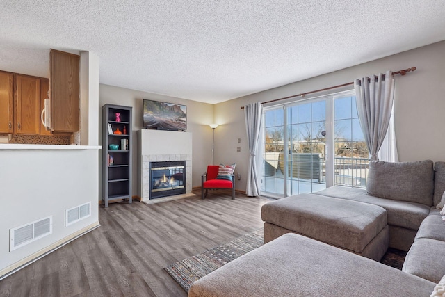 living room featuring a tile fireplace, light hardwood / wood-style flooring, and a textured ceiling