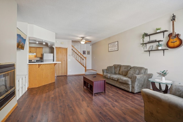 living room featuring ceiling fan, dark hardwood / wood-style floors, and a textured ceiling