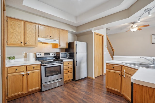 kitchen featuring under cabinet range hood, stainless steel appliances, dark wood-type flooring, a sink, and light countertops