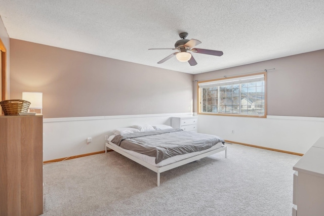 carpeted bedroom featuring a ceiling fan, baseboards, and a textured ceiling