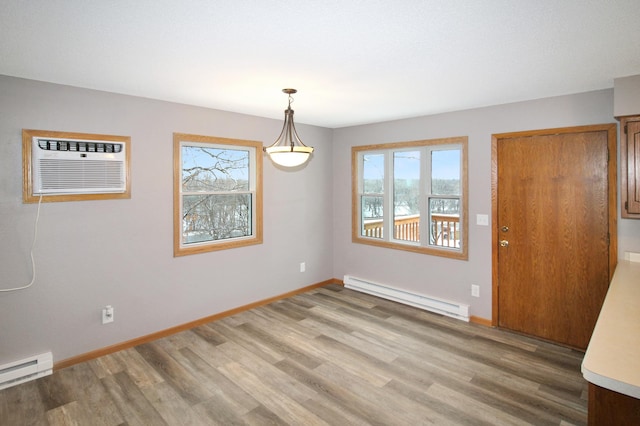 empty room with hardwood / wood-style floors, a baseboard radiator, and an AC wall unit