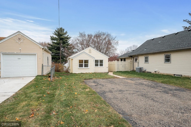 exterior space featuring a garage, central AC, a front lawn, and an outdoor structure