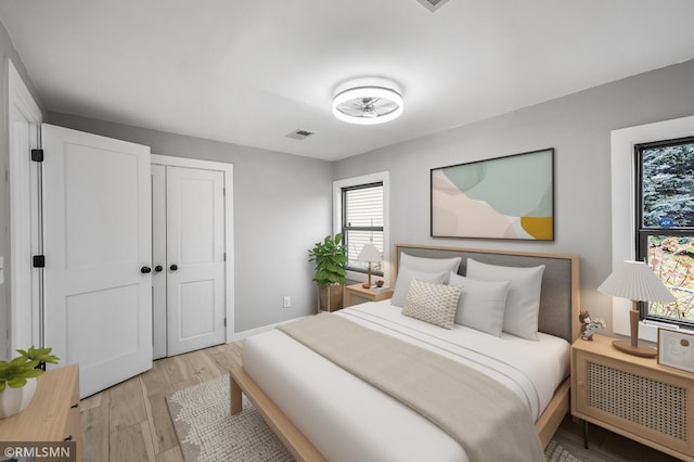 bedroom with light wood-type flooring, radiator heating unit, and a closet