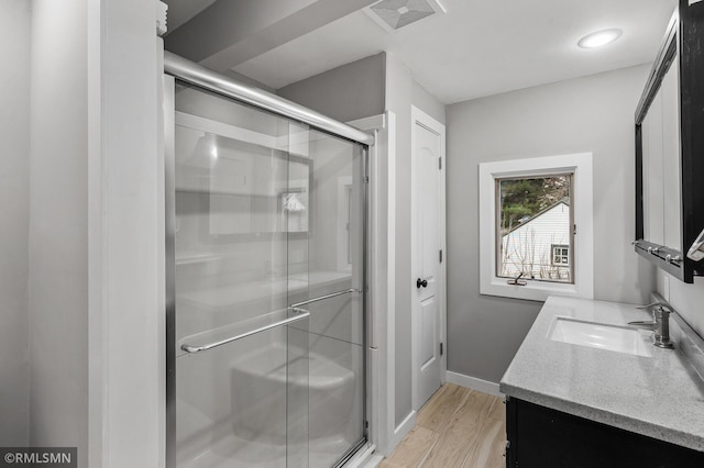 bathroom featuring vanity, wood-type flooring, and a shower with door