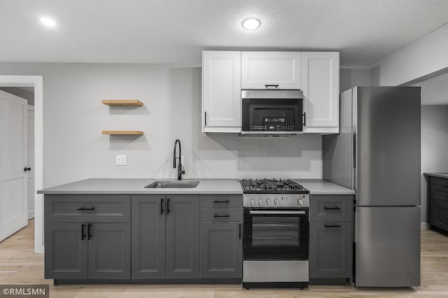 kitchen with sink, stainless steel appliances, light hardwood / wood-style floors, gray cabinets, and white cabinets