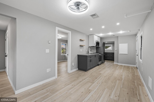 kitchen with ceiling fan, sink, stainless steel appliances, light hardwood / wood-style flooring, and white cabinets