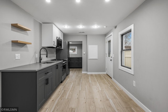 kitchen with gray cabinets, sink, light wood-type flooring, and appliances with stainless steel finishes