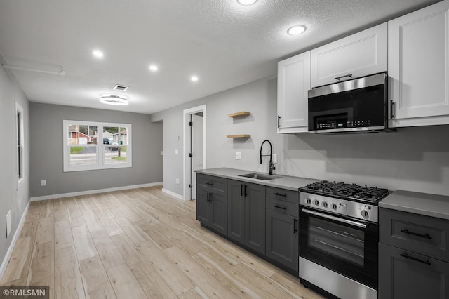 kitchen featuring white cabinets, stainless steel appliances, gray cabinets, and sink