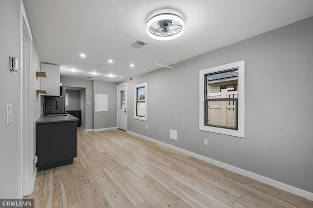 kitchen with a textured ceiling, ceiling fan, sink, and light hardwood / wood-style flooring