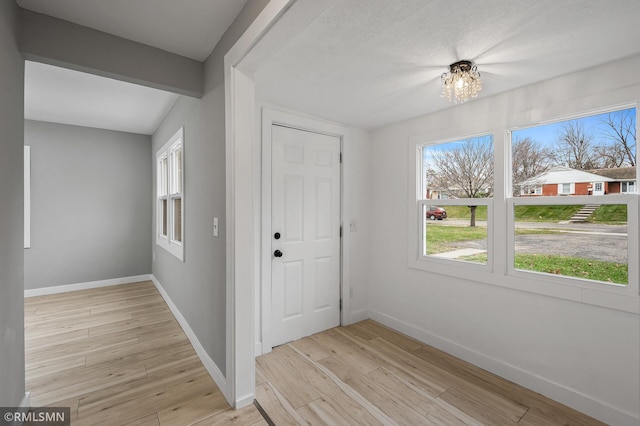 foyer featuring a chandelier, beam ceiling, and light hardwood / wood-style flooring