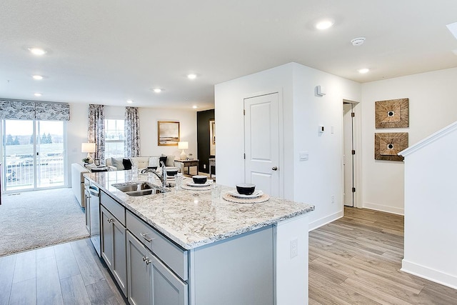 kitchen featuring a kitchen island with sink, sink, light hardwood / wood-style flooring, dishwasher, and gray cabinets